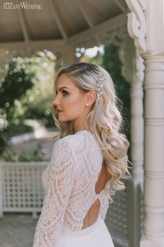 a woman with long hair wearing a white dress and holding her back to the camera