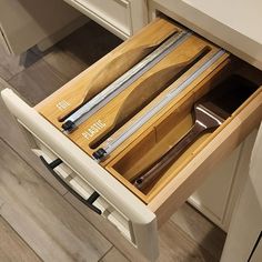 an open drawer in a kitchen with knives and spoons inside the drawers on both sides