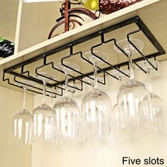 several wine glasses are hanging from a shelf