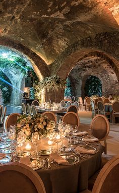 an indoor dining area with tables and chairs set up for formal function, surrounded by stone archways