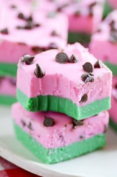 two pieces of pink and green ice cream with chocolate chips on top sitting on a white plate