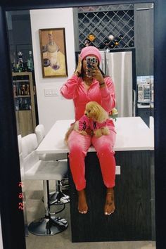 a woman in pink is taking a selfie with her teddy bear while sitting on the counter