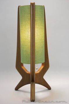 a wooden table lamp with a green shade on it's side and a white background