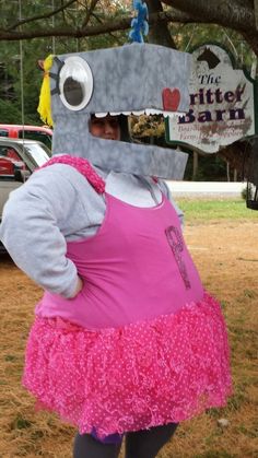 a woman in a pink dress standing under a tree with a sign on it's head