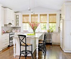 a kitchen with white cabinets and an island in the middle, surrounded by wooden flooring