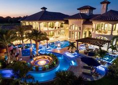 an aerial view of a mansion at night with pool and hot tub area in the foreground