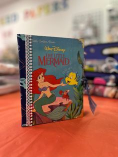 the little mermaid book is sitting on a table