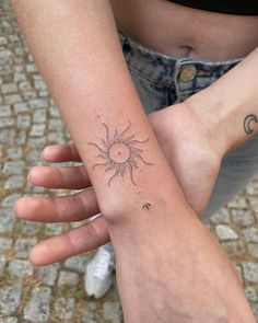 two people holding hands with tattoos on their arms and one has a sun in the middle