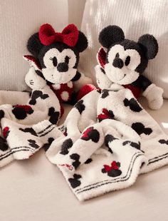 two mickey mouse stuffed animals are laying on a white bed with red and black polka dots