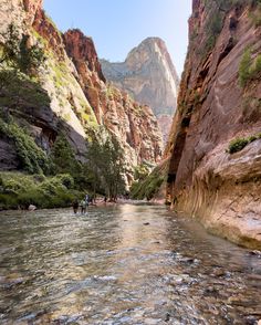 people are wading through the water in a narrow canyon with mountains in the background