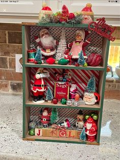 a shelf filled with christmas decorations and santa clause figurines on top of it