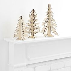 three wooden trees sitting on top of a fireplace