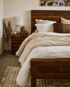 a bed with white linens and pillows in a small room next to a painting on the wall