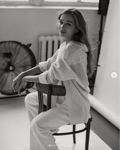 a woman sitting in a chair next to a fan