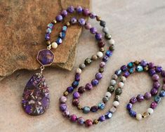 "Approx. 34\" L. Pendant size: 1.2\"x3\" Color, size, pattern may vary. Elevate your style with our enchanting Purple Sea Sediment Imperial Jasper Necklace, featuring a substantial stone pendant for a bold and distinctive look. Meticulously handcrafted, this necklace is not just a stunning accessory but also a symbol of stability and healing. The large Purple Sea Sediment Imperial Jasper pendant takes center stage, displaying a mesmerizing blend of deep purples and rich blues. Known for its stabilizing energy, this gemstone promotes a sense of calm and balance. The necklace goes beyond mere fashion, offering a connection to the earth's energies and a shield of healing crystal protection. Measuring approximately 34 inches, the knotted design showcases the natural beauty of Purple Sea Sedime Multicolor Jasper Spiritual Necklace, Spiritual Multicolor Jasper Necklaces, Crystal Protection, Crystal Beaded Necklace, Purple Sea, Imperial Jasper, Jewelry Knots, Jasper Necklace, Sugar Land