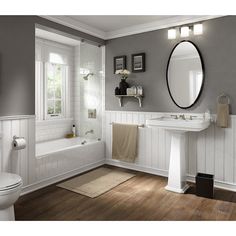 a white bathroom with gray walls and wood flooring is pictured in this image, there are two mirrors on the wall above the sink