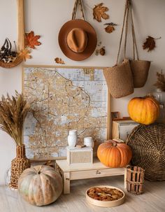 a table topped with lots of pumpkins next to a wall mounted map and hanging baskets