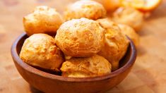 a wooden bowl filled with pastries on top of a table next to sliced oranges