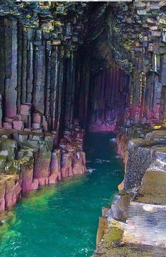 the water is blue and green in this cave with rocks on either side that are carved into cliffs