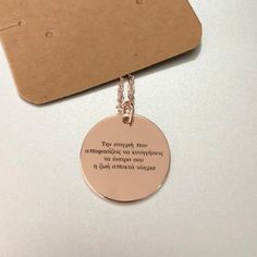 a necklace with a quote on it sitting next to a piece of paper that says,