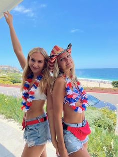 two beautiful young women standing next to each other wearing patriotic outfits and holding their arms in the air