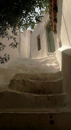 an alleyway with steps leading up and down to the door in whitewashed buildings