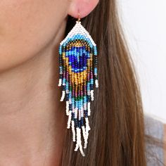 A lovingly hand-crafted, one-of-a-kind show stopper. Photos do NOT do them justice, you will be blown away in person! Teal, blue, olive, tan, pearl multi-colored earrings finished with stainless steel hardware for safety and comfort.Colors may vary slightly due to availability making each pair as unique as a peacock themselves. Each pair takes approximately 6 hours to complete due to the intricate design. Details: Handcrafted by artisans in Medellin, ColombiaMaterials: seed beads / stainless ste Blue Artsy Jewelry For Festivals, Artsy Blue Jewelry For Festivals, Blue Handmade Spiritual Earrings, Handmade Blue Spiritual Earrings, Unique Blue Beaded Earrings As Gift, Unique Blue Beaded Earrings For Gift, Artisan Blue Beaded Earrings As Gift, Artisan Blue Earrings For Festival, Unique Blue Beaded Earrings Nickel-free