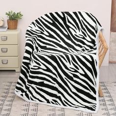 a black and white zebra print blanket sitting on top of a chair next to a dresser