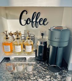 a coffee maker sitting on top of a counter next to bottles of liquid and glasses