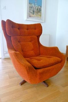 an orange chair sitting on top of a hard wood floor