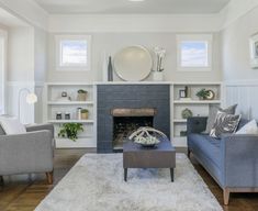 a living room with two couches and a fireplace in the center, surrounded by white shelving