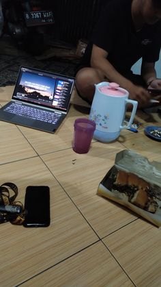 a person sitting on the floor with their laptop and cell phone in front of them