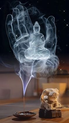 a buddha statue sitting on top of a wooden table next to a small bowl filled with rocks