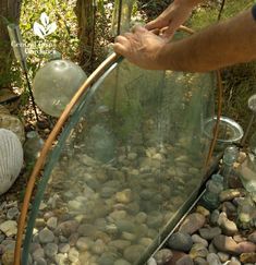 a man is holding a hose in his hand over some rocks and pebbles on the ground