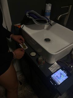 a person standing in front of a sink with a cell phone on the counter next to it