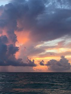 the sun is setting over the ocean with clouds in the sky and on the water