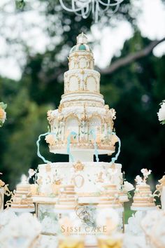 an elaborately decorated wedding cake is displayed in front of other cakes and desserts