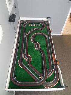 a toy race track set up in the corner of a room with carpeted flooring