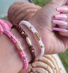 three different bracelets on someone's arm with pink and white beads in the middle