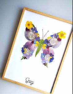 a painting of a butterfly with flowers on it's wings is displayed in a wooden frame