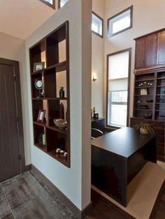 an office with wooden floors and open shelving units on the wall, along with a door leading to another room