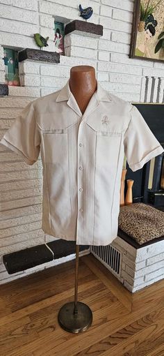 Cool 1970's Polyester ream Short sleeve Shirt! Button front, Two hidden chest pockets and a needlepoint TIKI God above left pocket! 19" across shoulders 10" sleeves 22" across chest 29" shirt Length Great condition " Iolani Hawaii Executive" Label Size Large Classic Cream Shirt With Pockets, Classic Camp Shirt With Lapel Collar, Classic Camp Shirt With Lapel Collar And Pockets, Vintage Button-up Shirt With Patch Pockets, Vintage Camp Shirt With Pockets And Relaxed Fit, Vintage Single Breasted Tops For Spring, Vintage Shirt With Button Cuffs And Relaxed Fit, Retro Beige Button-up Shirt, Vintage Summer Shirt With Button Cuffs