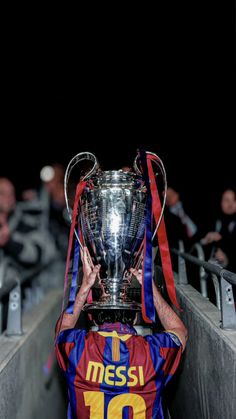 the messi trophy is held up in front of his head as he looks down at it