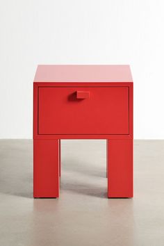 a small red table with one drawer on the top and two drawers on the bottom