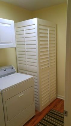 a washer and dryer are in the corner of this laundry room with white shutters