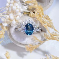 a blue and white diamond ring sitting on top of a shell with pearls around it