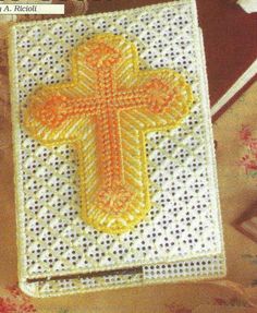 a cross is shown on the side of a white book with yellow trimmings