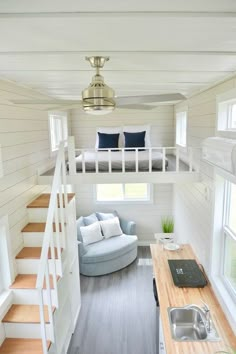 the interior of a tiny house with white walls and wood flooring, stairs leading up to a loft bed