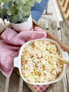 a bowl of macaroni and cheese sitting on a tray next to a potted plant