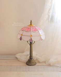 a pink and white lamp sitting on top of a wooden table